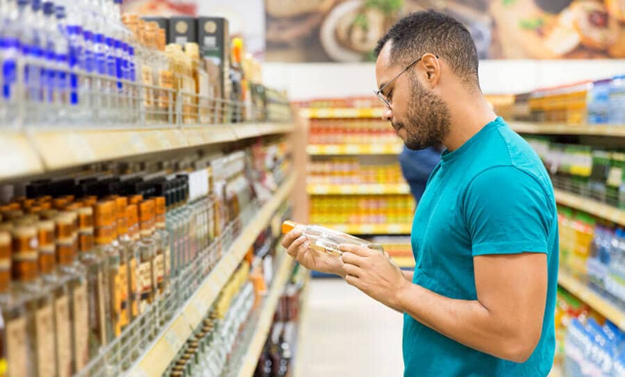 consumer trying to figure out what product is ideal form a selection of options in a aisle at a Supermarket